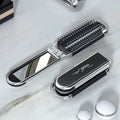 Compact hairbrush with integrated mirror |